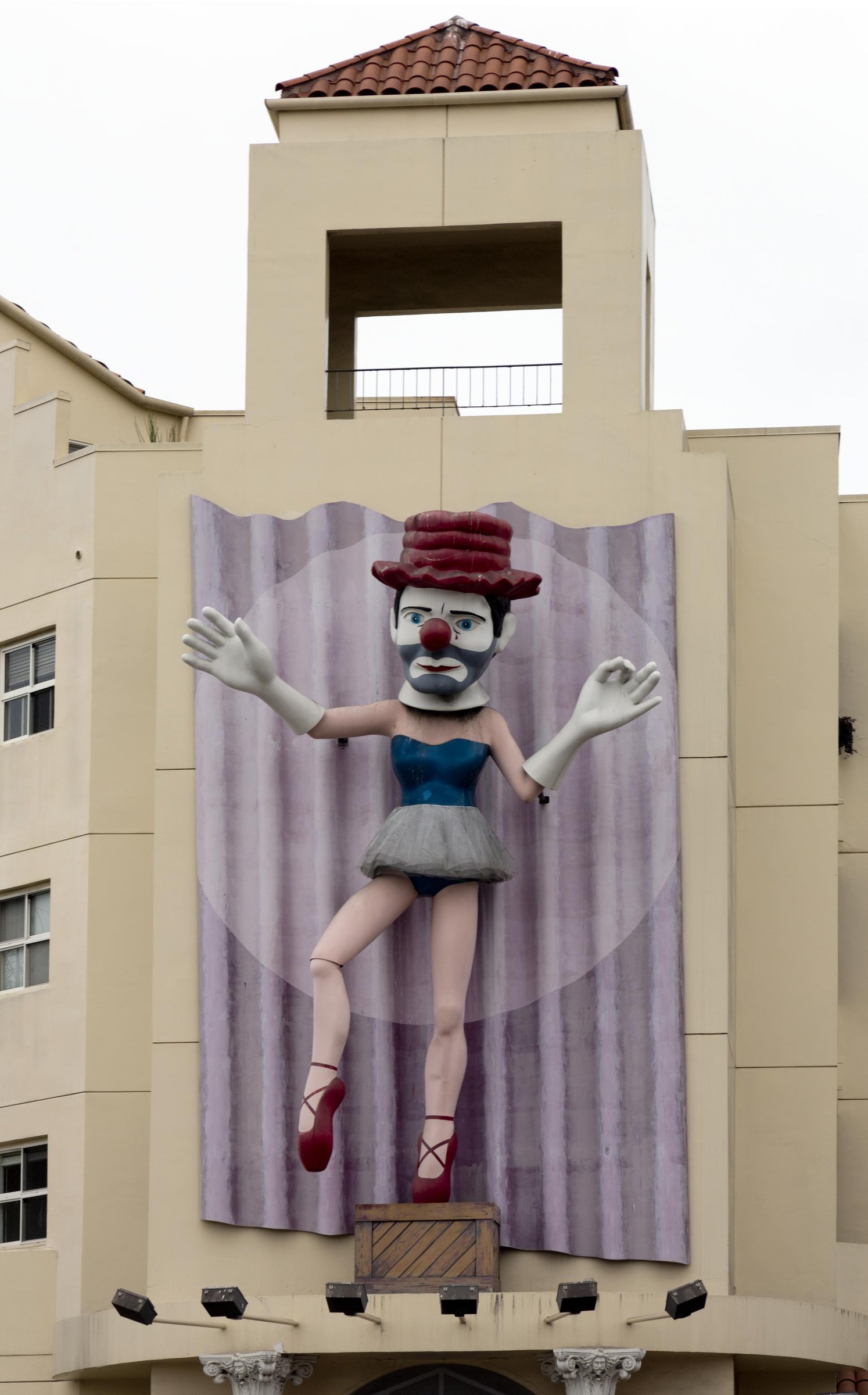 Monumental public mural of a clown wearing pointe shoes and a tulle skirt on a Venice, Los Angeles building facade.