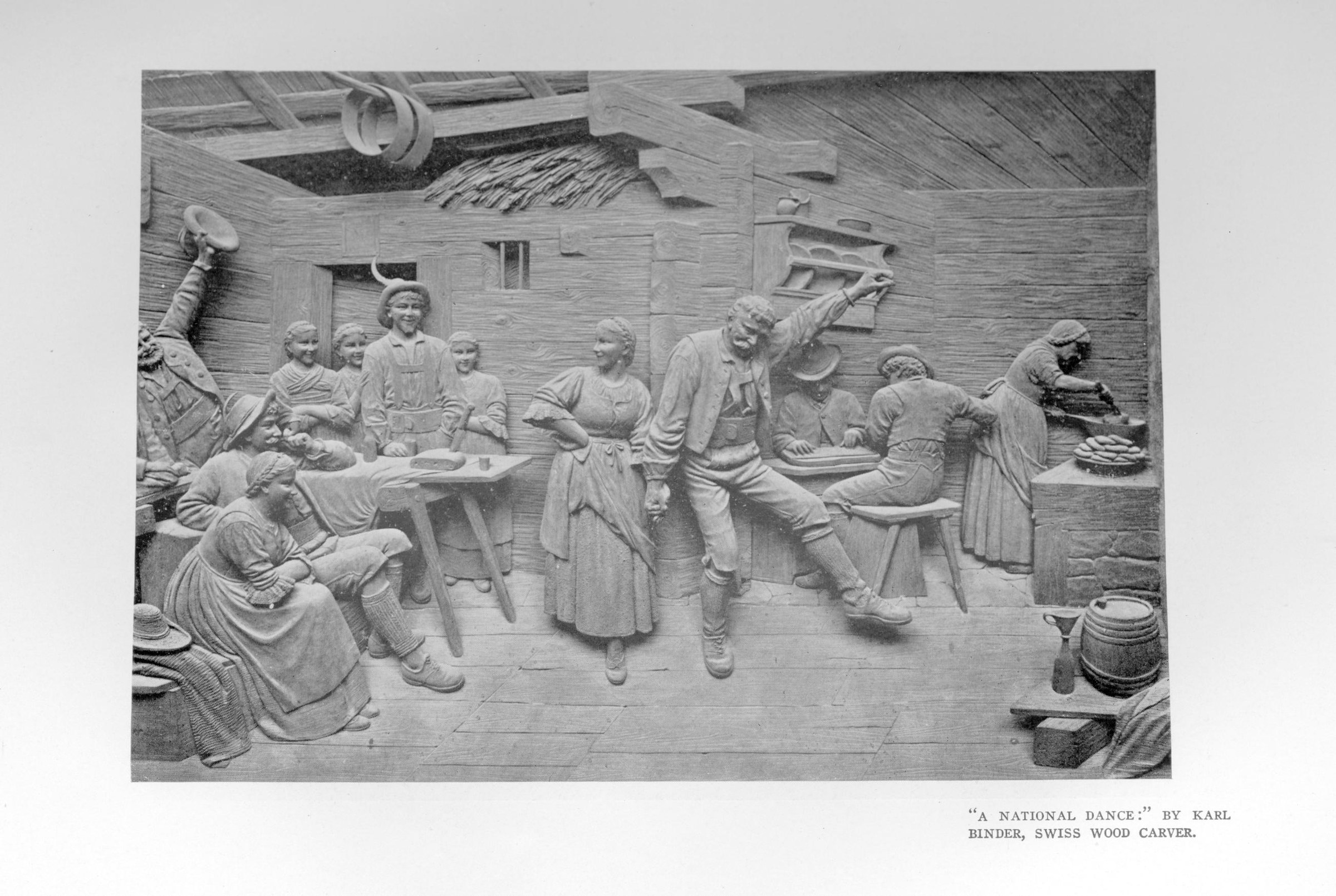 Wood relief carving showing a village celebration with couples dancing and onlookers seated and standing around them in a timber-beamed interior.