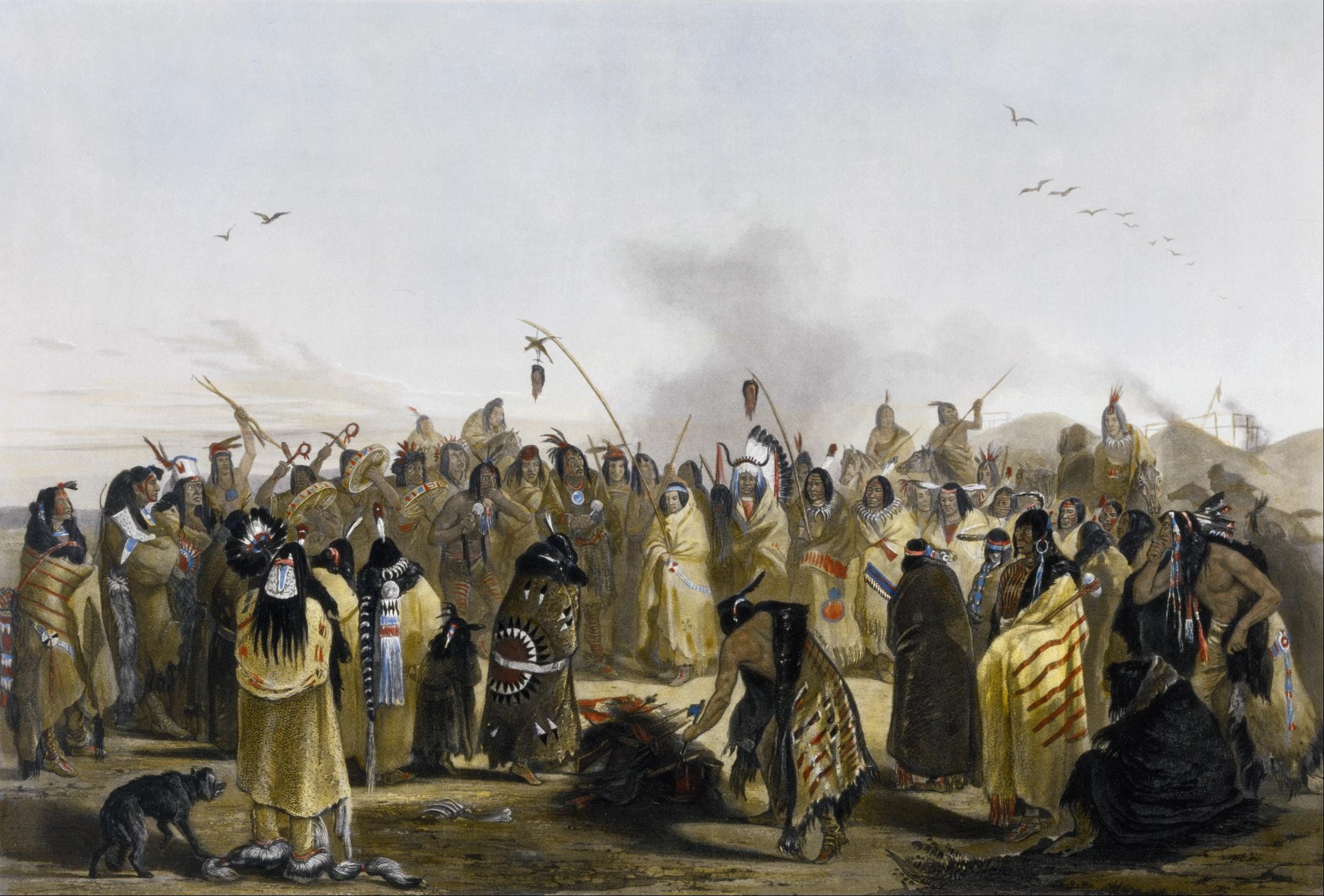Dense gathering of Indigenous people in hide clothing holding raised weapons, assembled in an open landscape with pale sky.