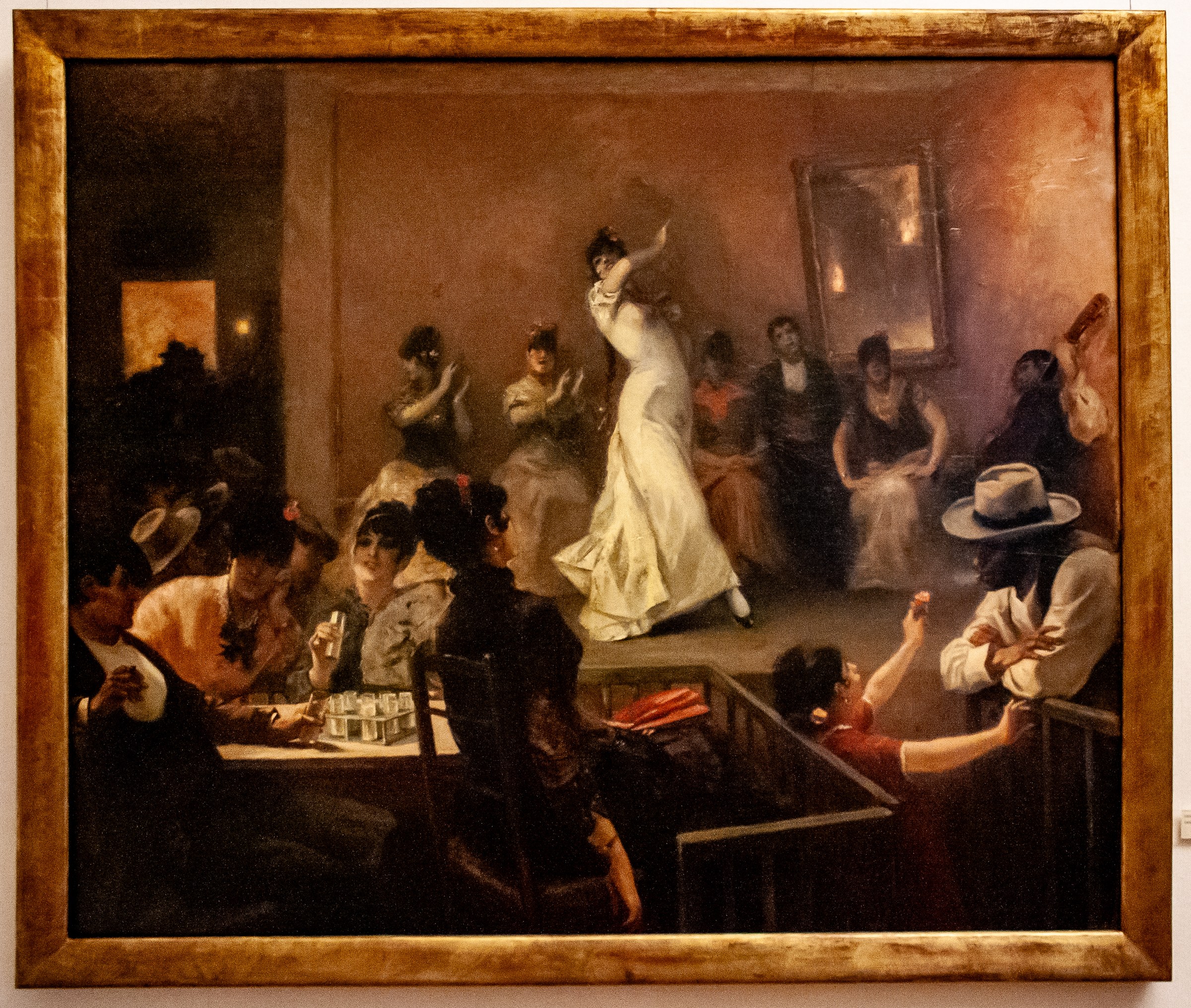 A woman in white dress performs an arched backbend before tavern spectators in a dimly lit interior.