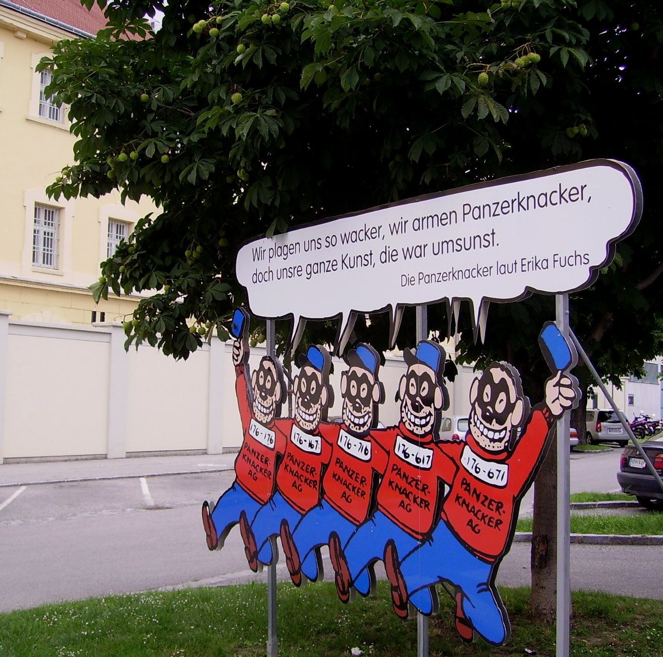 Five cartoon soldiers in red uniforms jumping in unison with grinning faces, on a street sign with German text above them.