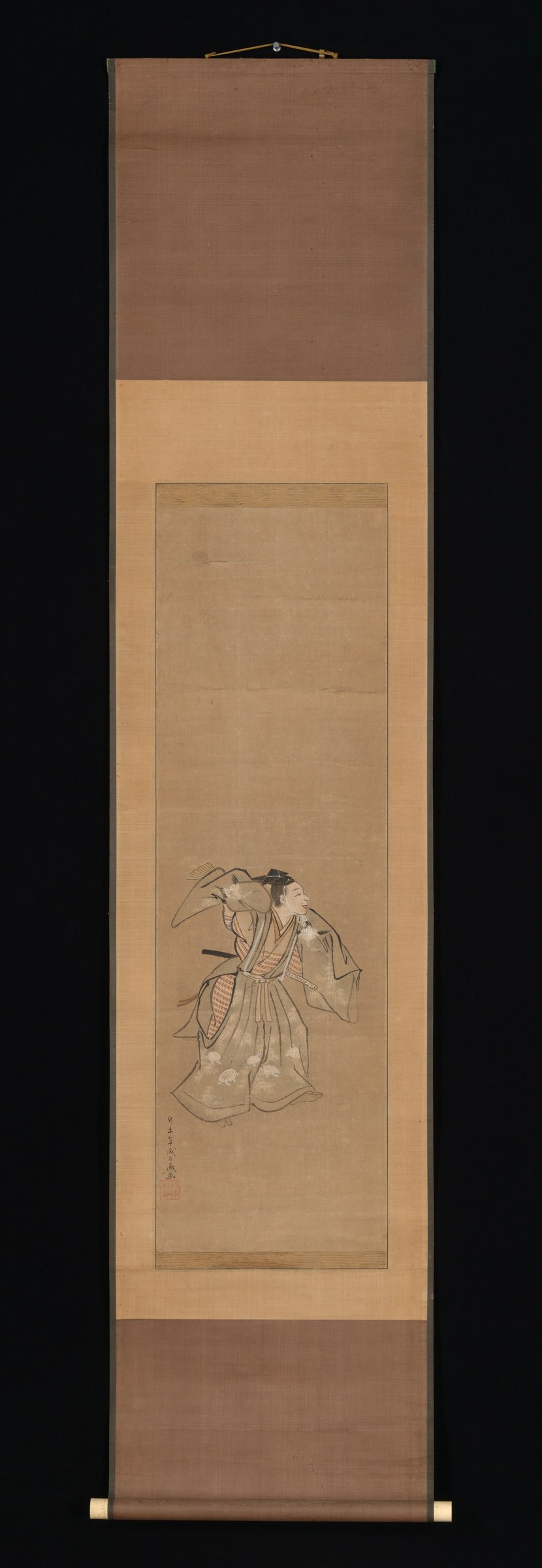 A single figure in formal layered robes stands upright with left arm raised, shown in ink and wash on a vertical hanging scroll.