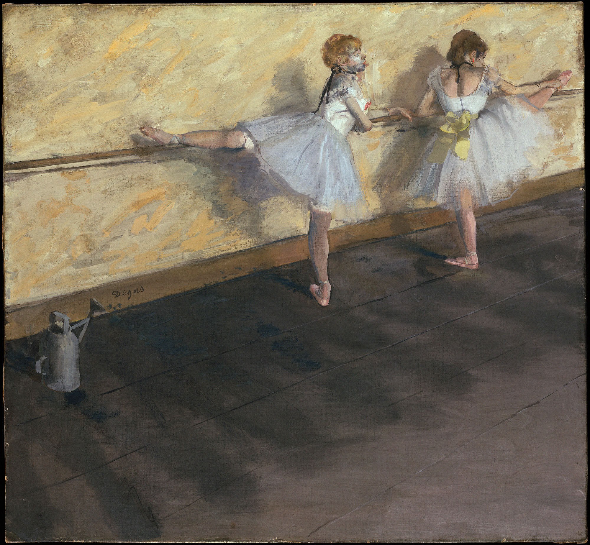 Two young ballet dancers at a wooden barre in a sunlit studio, legs extended, practicing classical positions.