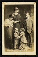 Studio photograph of two small children in dance positions flanked by two adults in late 19th-century dress.