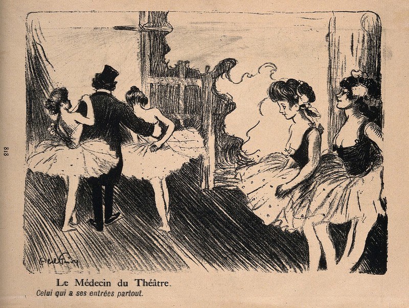 A doctor in top hat and formal dress sits between two young ballet dancers in tutus in a theatre setting, gesturing animatedly while they listen passively.
