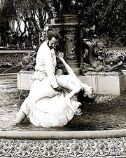 Two dancers in a close embrace in a garden, performing Argentine tango in mid-movement.
