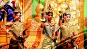 Multiple Cambodian dancers in elaborately costumed Apsara poses with pointed crown headdresses, fitted bodices, and tubular skirts, arranged in rows against a