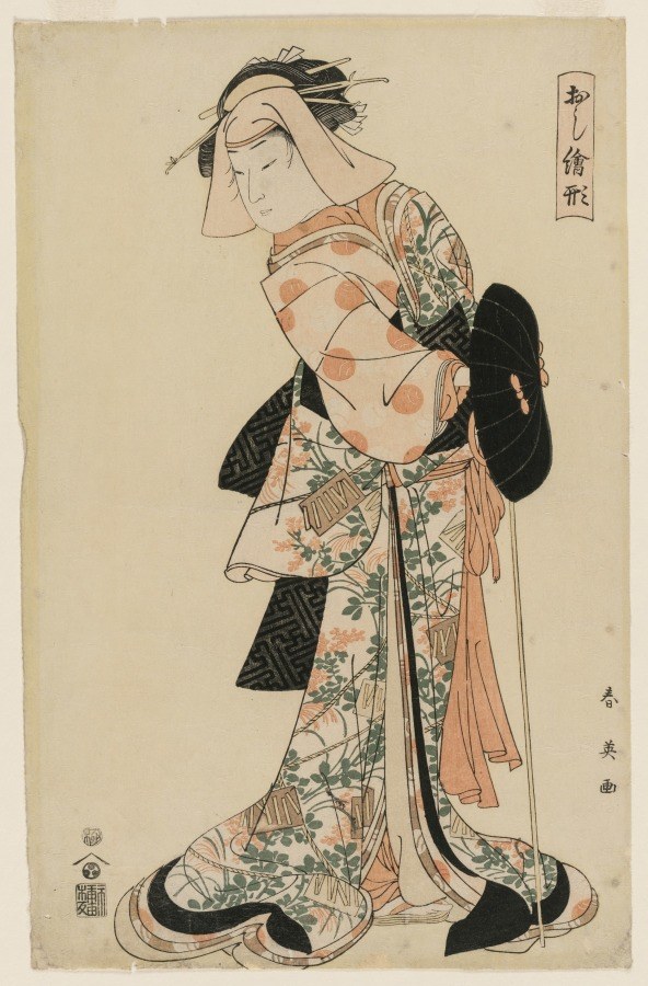 A Japanese woodblock print of a male Kabuki actor in female role, wearing patterned robes and holding a poised, formal stance.