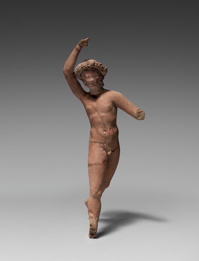 Terracotta figurine of a youthful male nude with left arm raised high, head tilted upward, in a dynamic celebratory pose.