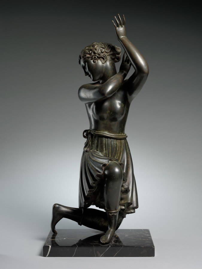 Bronze sculpture of a kneeling male dancer in classical pose with lifted torso and overhead arm reach, on marble base.