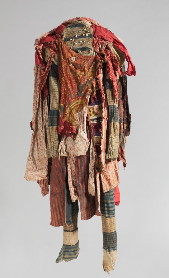 Carved wooden mask and layered patchwork textile costume representing an Egúngún ancestral spirit figure.