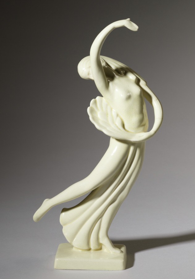 Marble or plaster sculpture of a single female dancer with raised left arm, flowing drapery, and uplifted gaze, titled Fan Dancer.