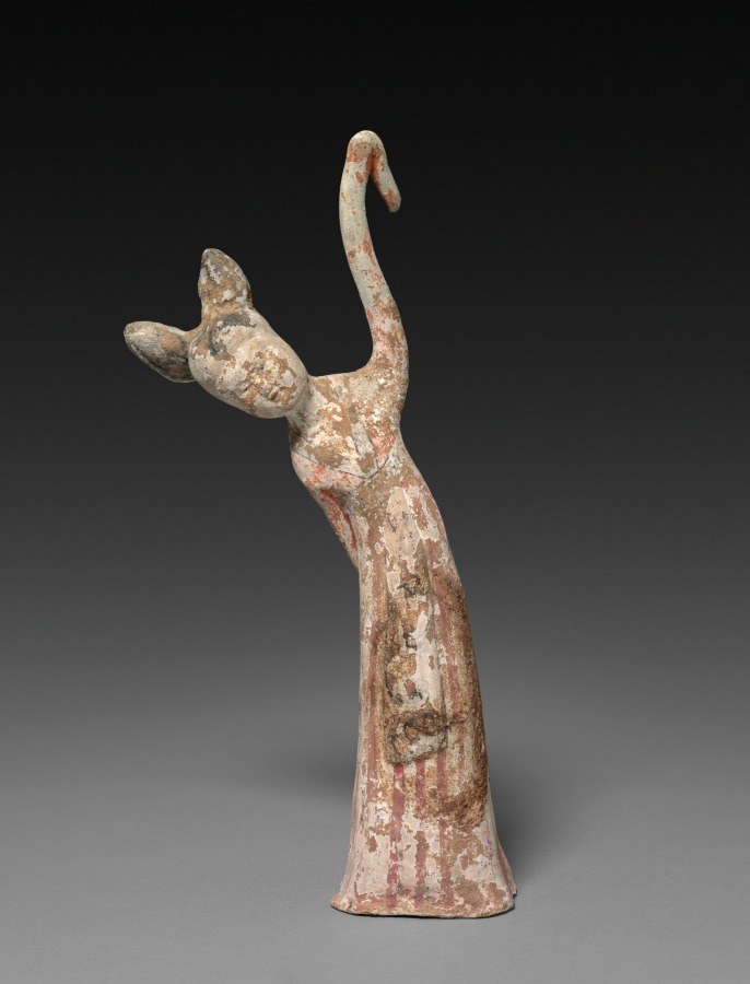 Terracotta figurine of a standing female dancer with right arm raised and left arm extended, wearing draped garment, showing cream and red patina.