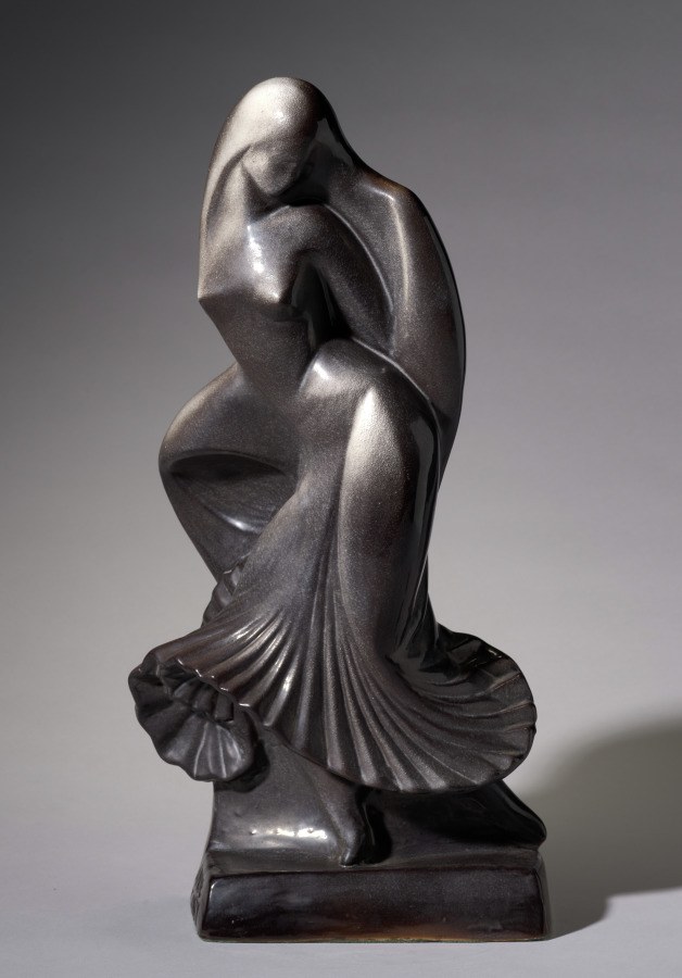 Cast bronze sculpture of a female dancer in extreme forward fold, head toward knees, arms drawn inward, standing on decorative drapery base.