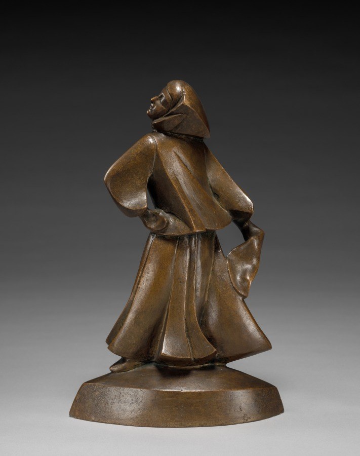 Bronze sculpture of a dancer with tilted head and flowing skirt, arms extended, spiraling in motion on a circular base.