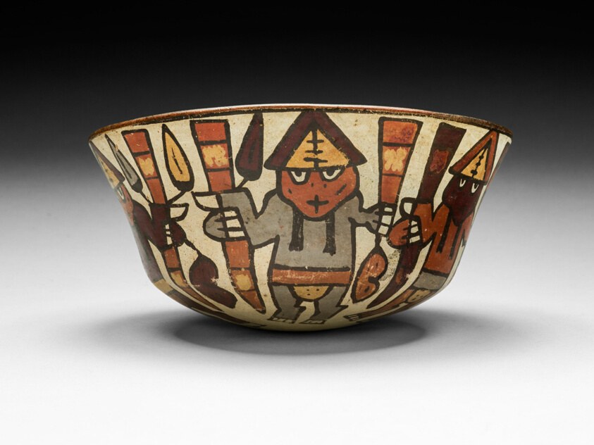 Cream-colored ceramic bowl interior showing central figure in pointed headdress surrounded by repeated dancing figures and geometric patterns in brown pigment.