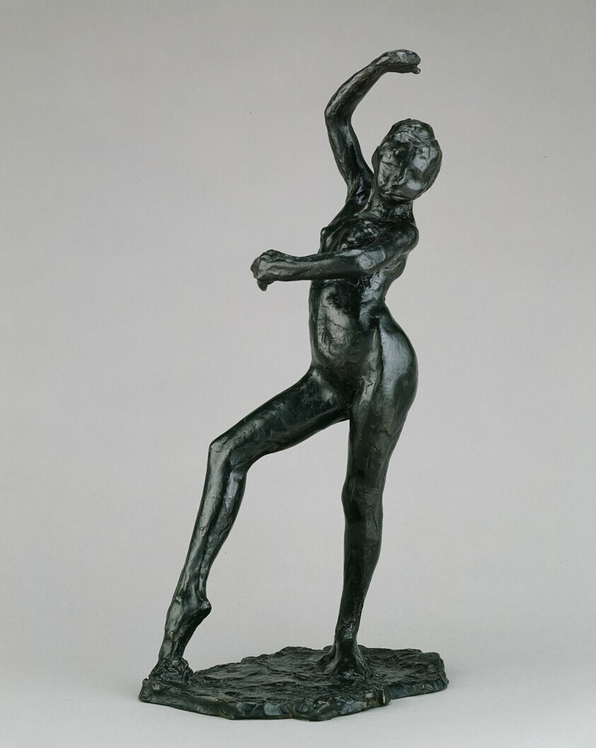 Bronze sculpture of a female figure in an arched, spiraling pose with left arm raised overhead and right knee bent.