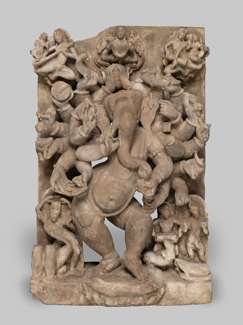 Stone relief of multi-armed Ganesha in dynamic pose surrounded by smaller celestial figures in varied gestures.