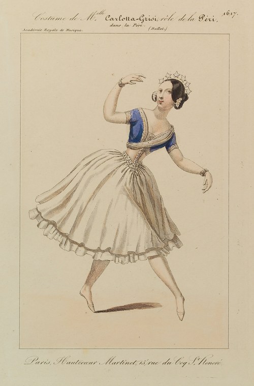 A female ballet dancer in pale skirt and blue corsage, poised on one foot with arms gracefully raised, wearing an ornate headdress.