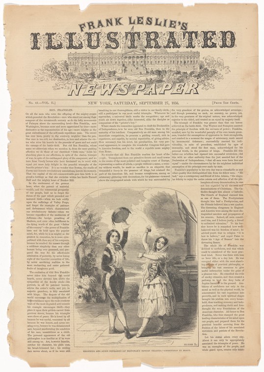 Two young women in theatrical costume perform acrobatics; one is suspended horizontally while the other stands below with arms raised in support.