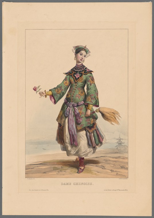 A woman in elaborate green embroidered silk robes with jeweled headdress and purple sash stands upright, holding a flowering branch and fan, posed against a