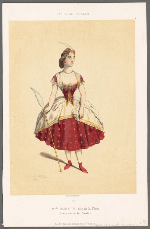 Woman in red silk tutu and burgundy bodice holding feathered wings, standing in graceful pose with gaze uplifted.