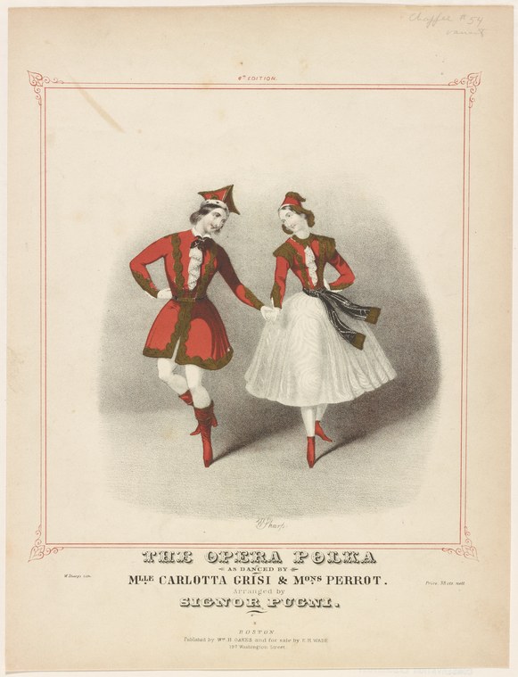 Two female dancers in red jackets and white skirts face each other in a posed theatrical stance, wearing red heeled shoes and headpieces.
