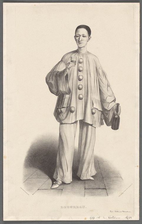 A man in white tunic and outer robe stands upright with composed expression, hands at his sides, representing the Pierrot character.