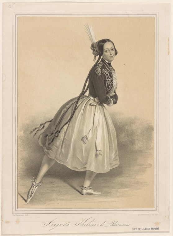 Female ballet dancer in a dark jacket and pale skirt with plumed headdress, captured mid-turn, trailing drapery flowing across the stage.