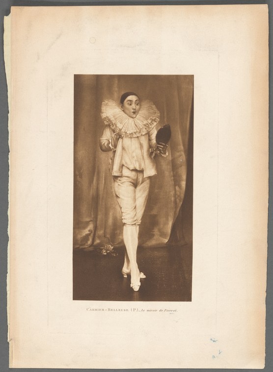 A pale figure in white Pierrot costume with large upright collar stands alone against a brown curtain, arm extended in a theatrical gesture.