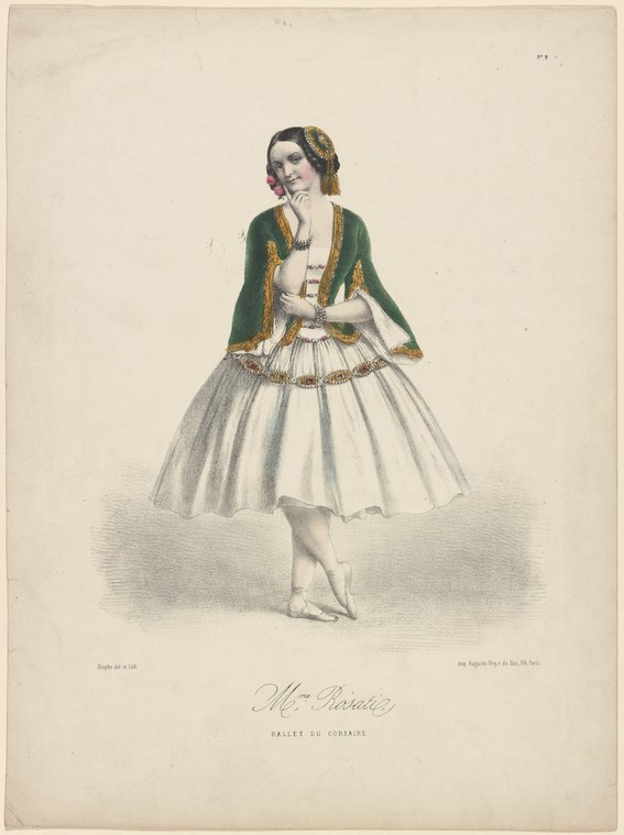 A ballerina in a white tulle skirt and green velvet jacket stands in a contemplative pose, hand to her face, gazing downward.