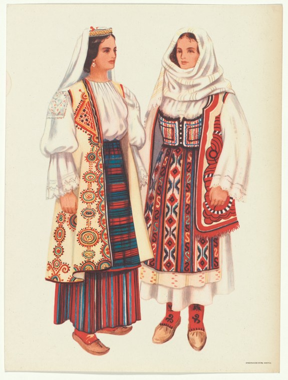 Two women stand facing each other wearing embroidered Balkan folk costumes with vests, layered skirts, and headscarves.