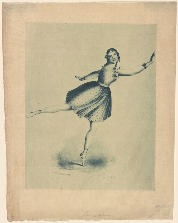 A woman in a polka-dot theatrical skirt balances on one leg in an extreme arabesque, her upper body tilted forward and arms raised in classical ballet position.