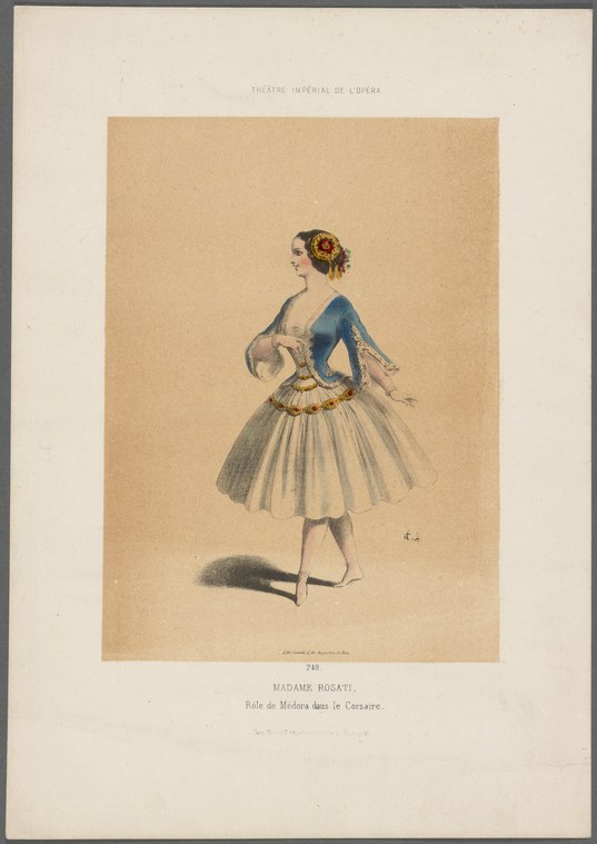Woman in dark blue jacket and pale tulle skirt, arms in ballet position, standing alone in studio light.