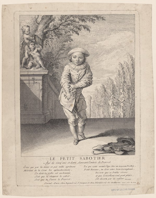 A child in white Pierrot costume stands in an asymmetrical dance pose with raised arms in a formal garden setting.