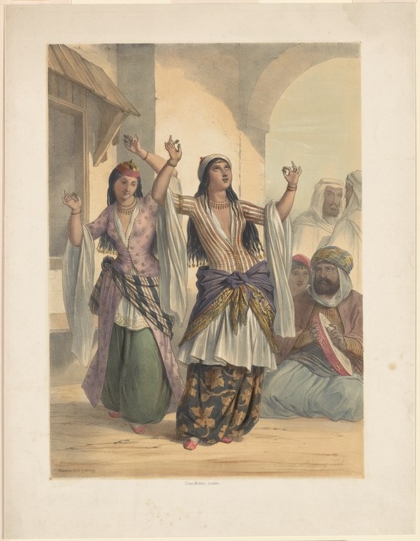 Two women in ornate Middle Eastern dress dance with raised arms and open palms inside a columned hall, observed by three turbaned men seated on the floor.
