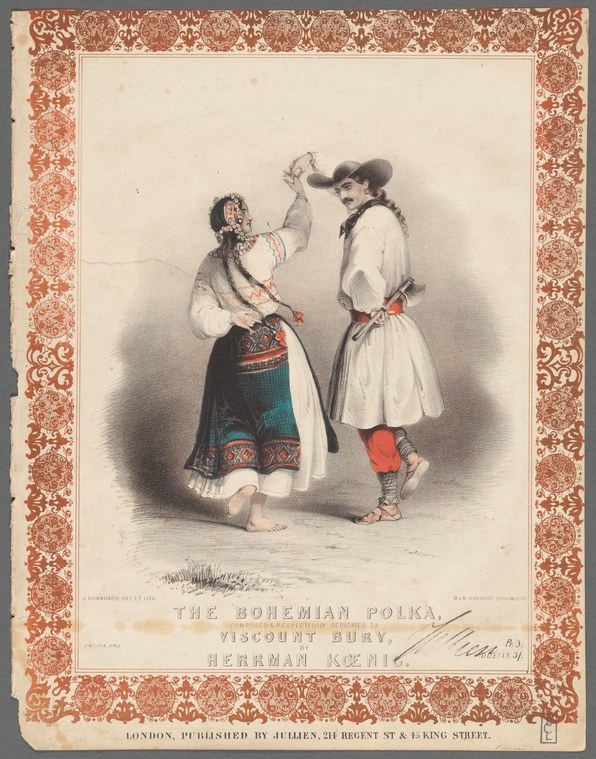 Two women in Bohemian folk dress perform a polka together, arms raised, on a plain stage framed by an ornate border.