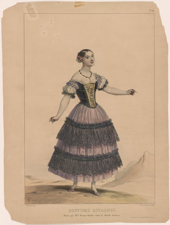 A young woman in a gold corset and tiered lace skirt stands in a balletic pose, arms open, in Spanish theatrical costume.