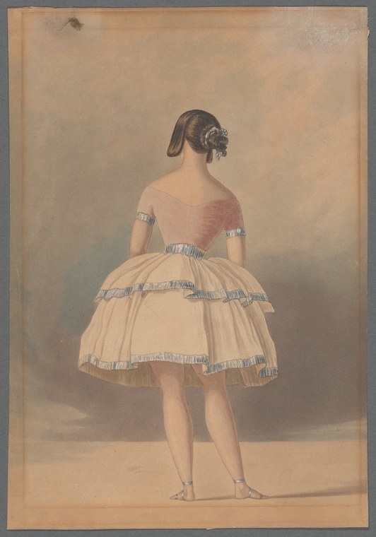 A young female ballet dancer in a pale pink bodice and tiered ivory tulle skirt stands facing three-quarter rear against a neutral background.