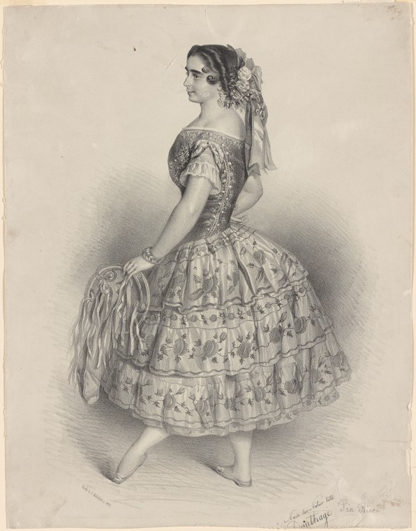 A woman in a romantic-era ballet costume stands posed, wearing a full patterned skirt with ruffles, off-shoulder bodice, and flowers in her hair.