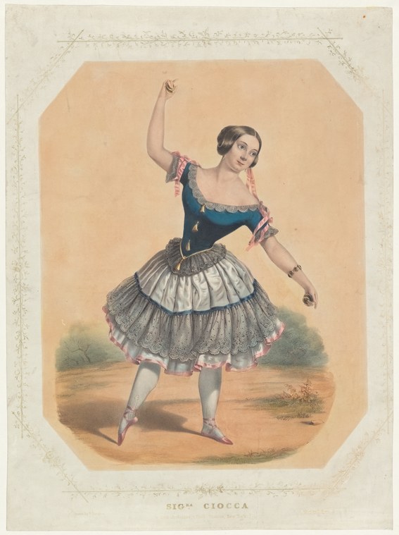Woman in romantic ballet costume with dark bodice, white tulle skirt, and pink pointe shoes, posed with raised arm.