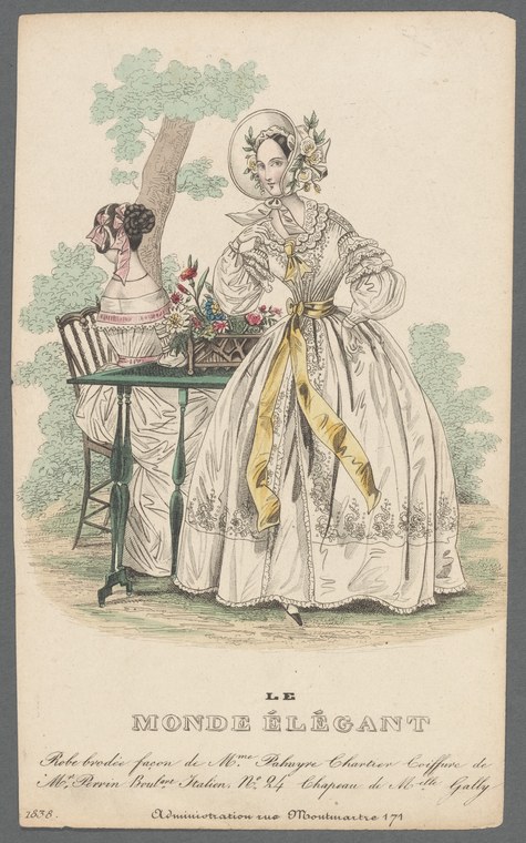 A woman in a white Regency gown with gold sash stands in a garden, posed to display her elegant dress and refined bearing.