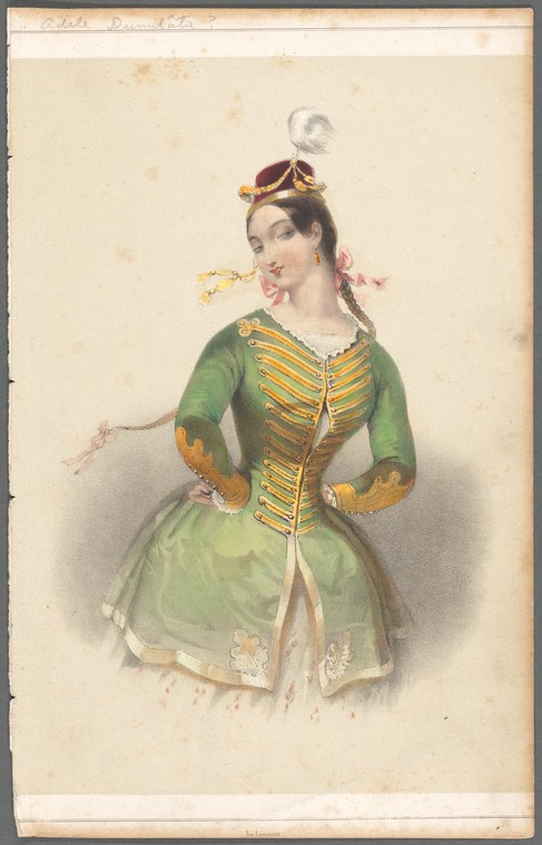 Woman in green military jacket with gold trim and red shako, arms akimbo, animated expression, hands on hips in theatrical pose.