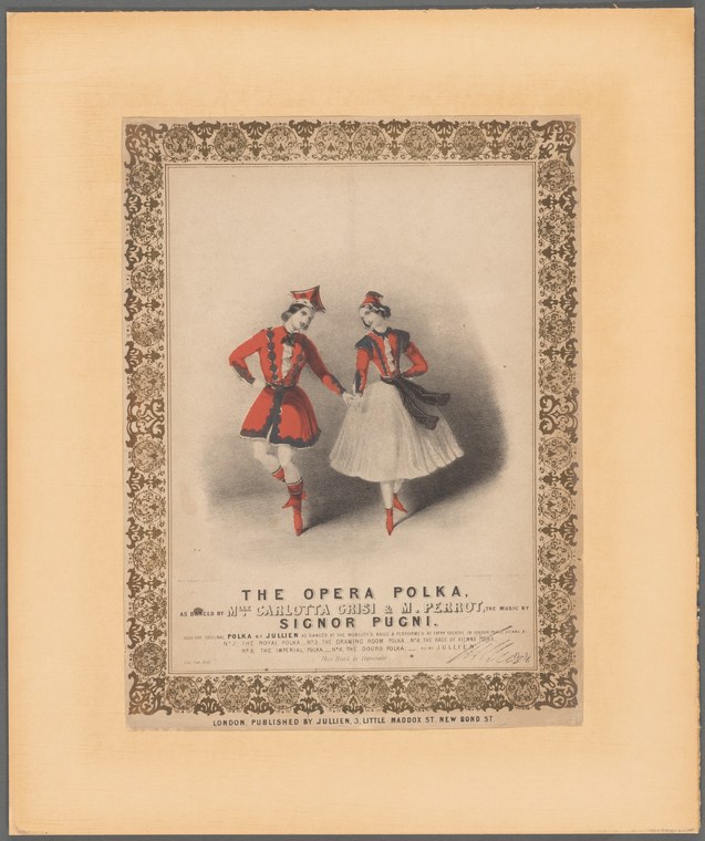 Two female dancers in red jackets and white skirts stand in conversation, one with hand on hip, the other reaching toward her companion.