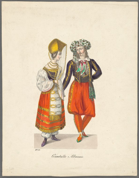 A man and woman in Albanian costume stand motionless against a plain background. She wears a tall gold headdress, embroidered shirt, and red skirt; he wears a