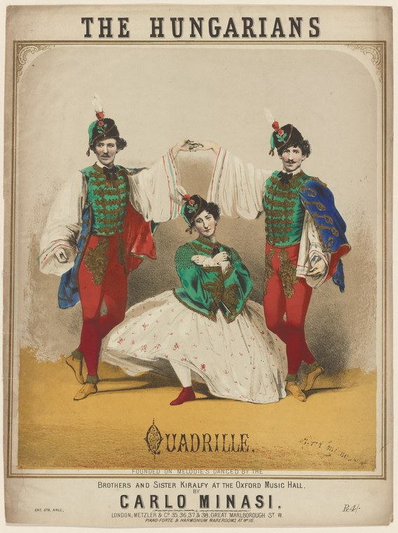 Four dancers in Hungarian embroidered costumes: three men standing in colorful vests with feathered headdresses, one woman seated in a green jacket and white