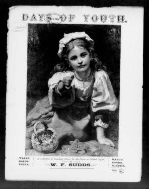 Seated girl in 1880s dress holding a small dog, studio portrait photograph with printed credit to W. F. Sudds.