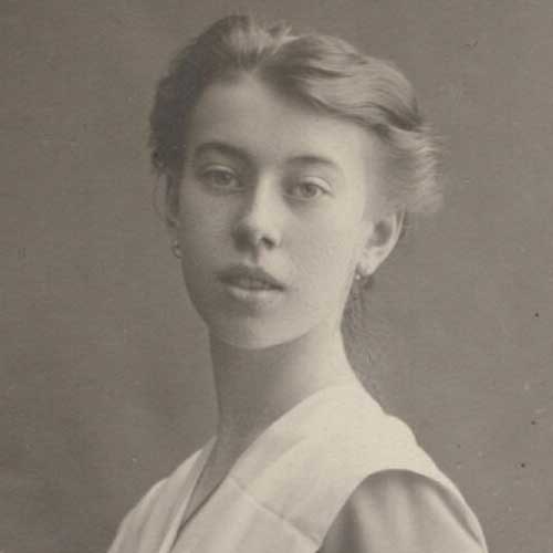 Black-and-white studio portrait of a young woman in early 20th-century dress with upswept hair, facing the camera.