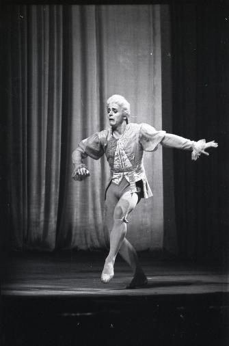 Mikhail Baryshnikov in 18th-century costume, posed mid-leap on stage with arms spread and one leg extended.