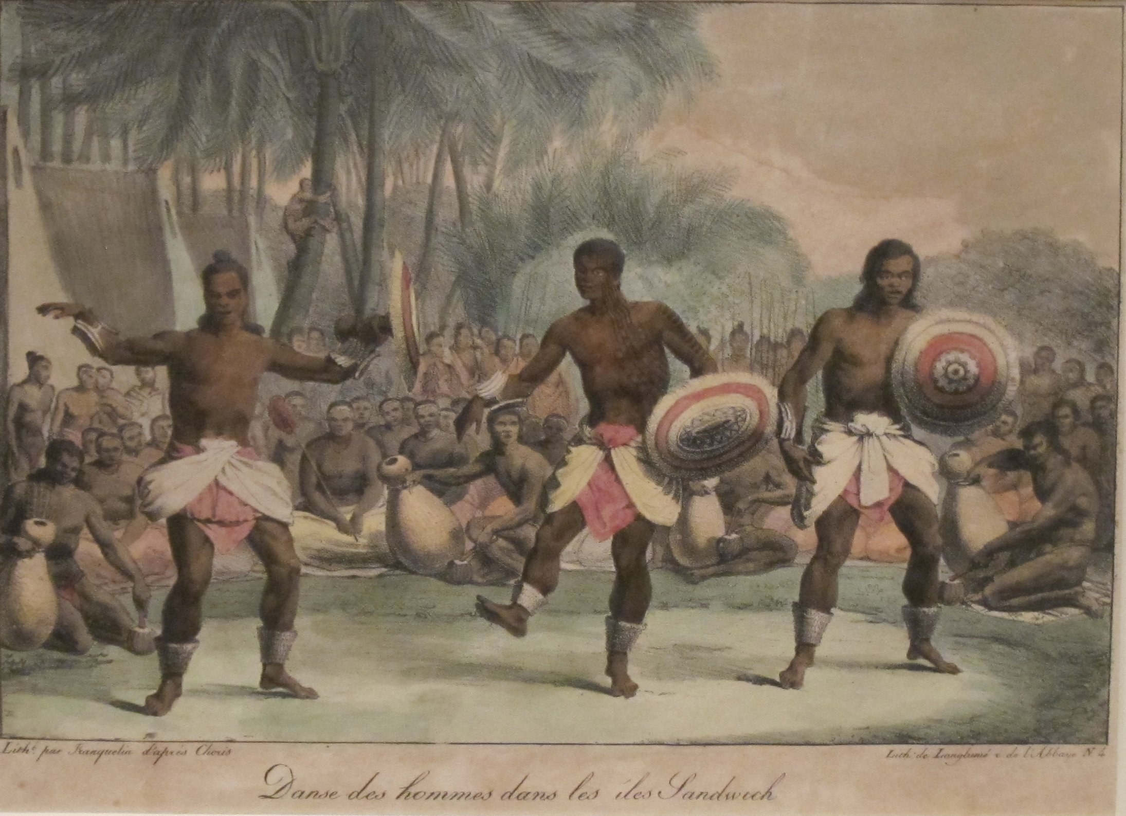 Three shirtless Hawaiian men in dynamic grounded postures with raised arms, surrounded by dozens of seated observers beneath tall palm trees.